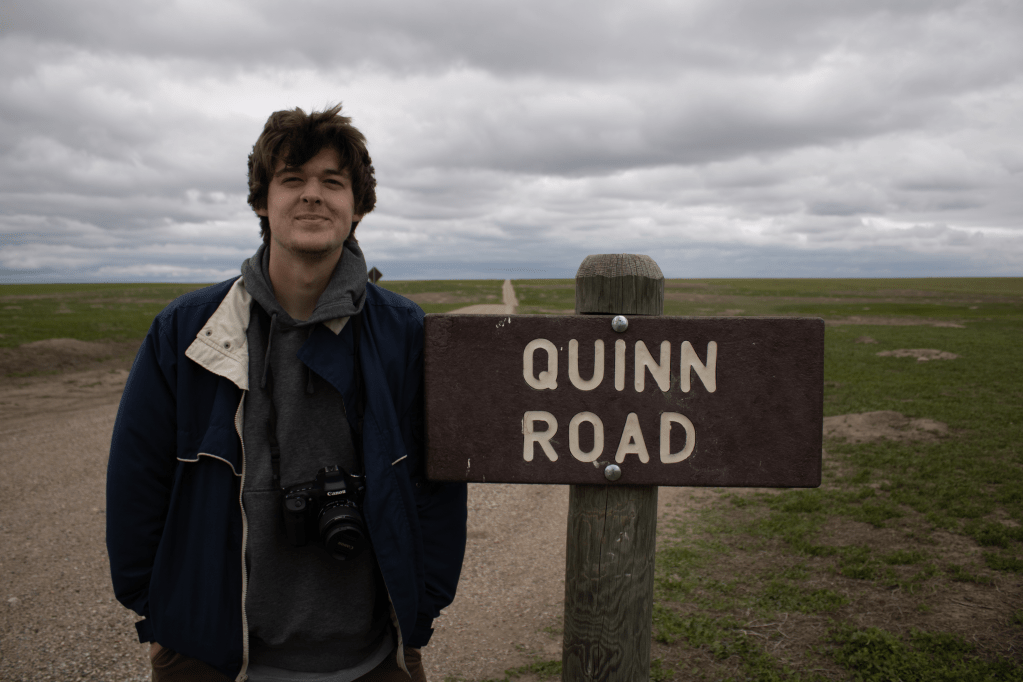Quinn standing next to a sign labled 'Quinn Road'